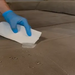 Demonstração de impermeabilização de um sofá com gotas de água repelidas